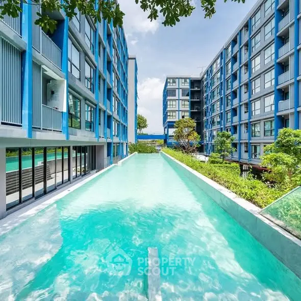 Luxurious modern apartment complex with stunning pool and lush greenery.