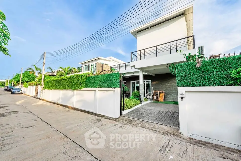 Modern two-story house with lush greenery and sleek design in a serene neighborhood.
