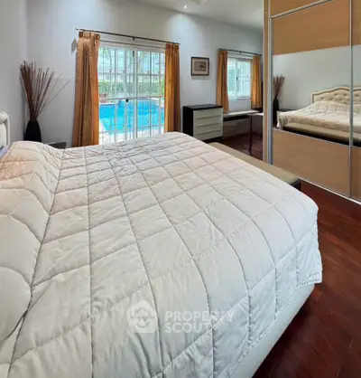 Spacious bedroom with pool view and mirrored wardrobe, perfect for relaxation and comfort.