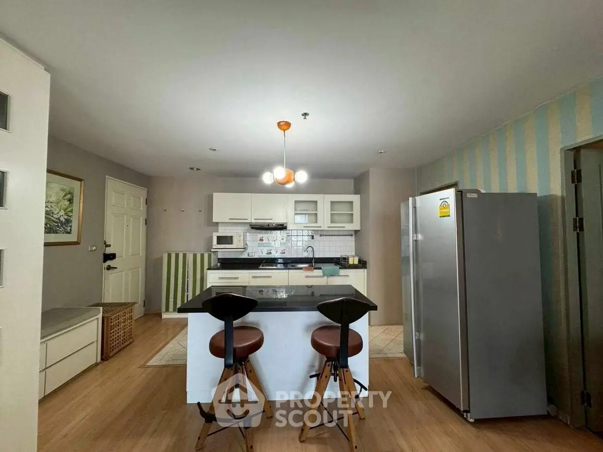 Modern kitchen with island, stylish stools, and sleek appliances in a contemporary home.