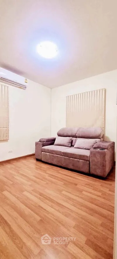 Cozy living room with wooden flooring and comfortable sofa, perfect for relaxation.