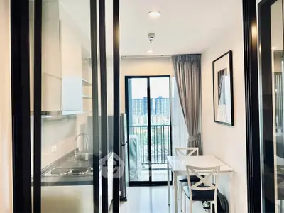 Modern kitchen with dining area and city view, featuring sleek design and ample natural light.