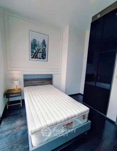 Modern bedroom with sleek design and cityscape artwork, featuring a comfortable bed and stylish nightstand.