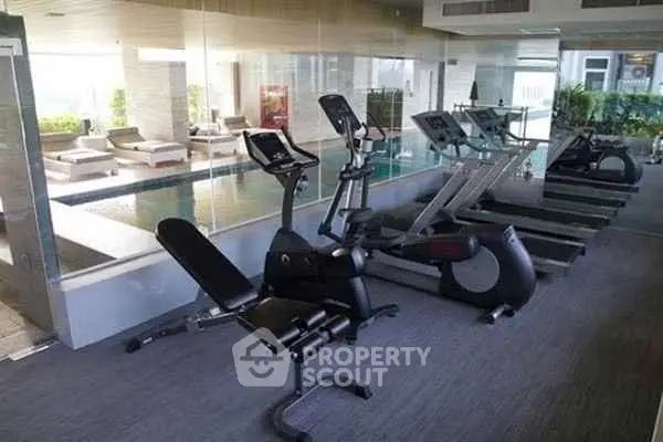 Luxurious gym with modern equipment and pool view in upscale residential building.