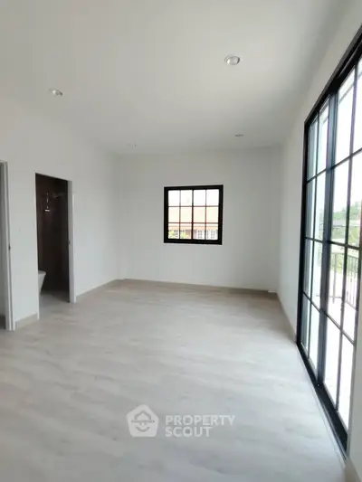 Spacious and bright room with large windows and modern flooring, perfect for customization.