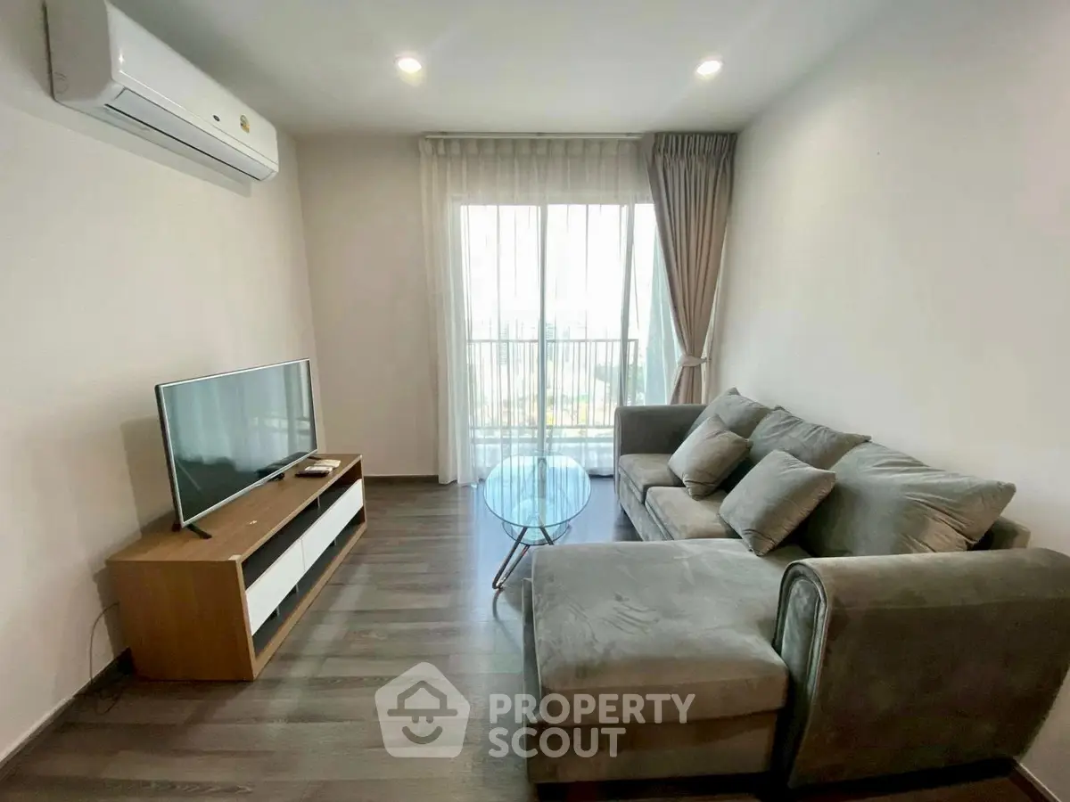 Modern living room with cozy sofa, flat-screen TV, and large window for natural light.