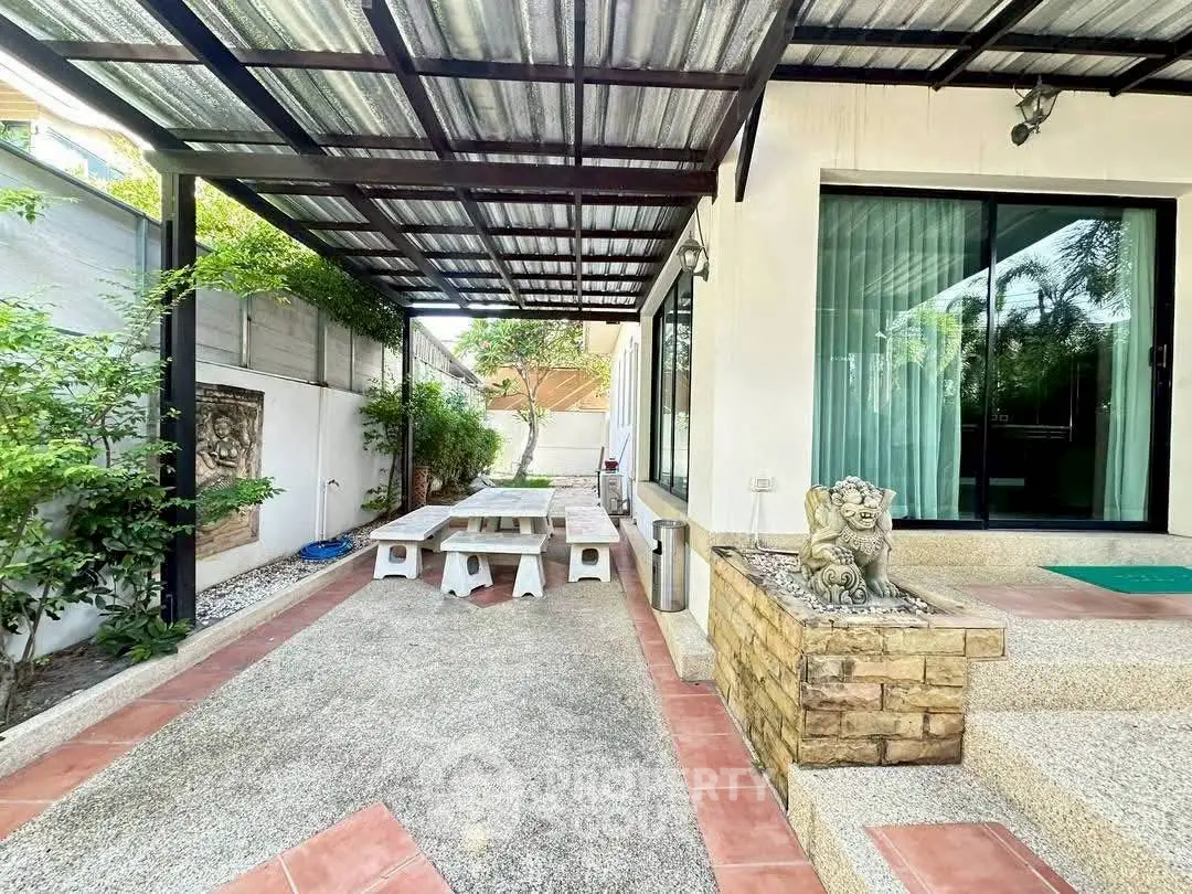 Charming outdoor patio with covered seating area and lush greenery, perfect for relaxation and entertaining.