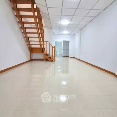 Spacious interior with wooden staircase and tiled flooring, ideal for modern living.
