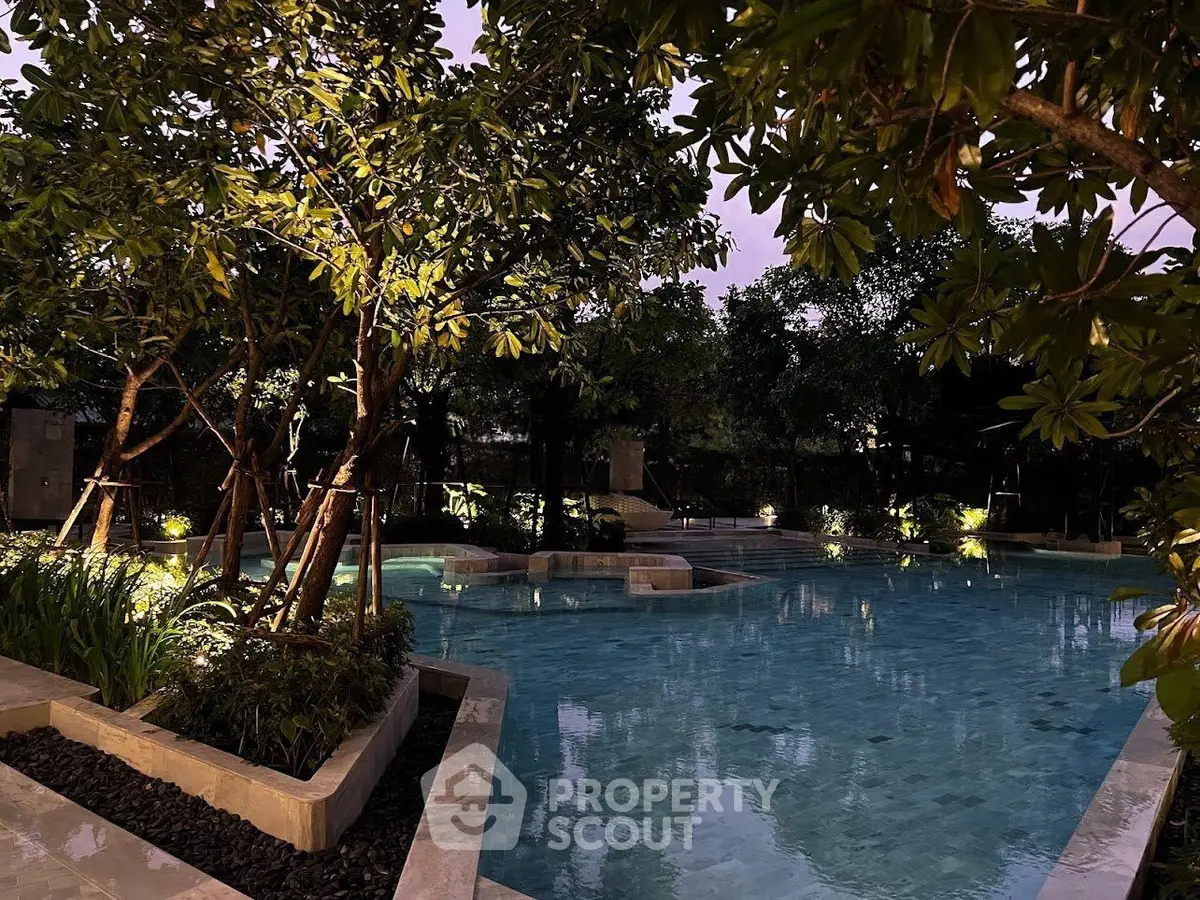 Luxurious outdoor pool surrounded by lush greenery and ambient lighting