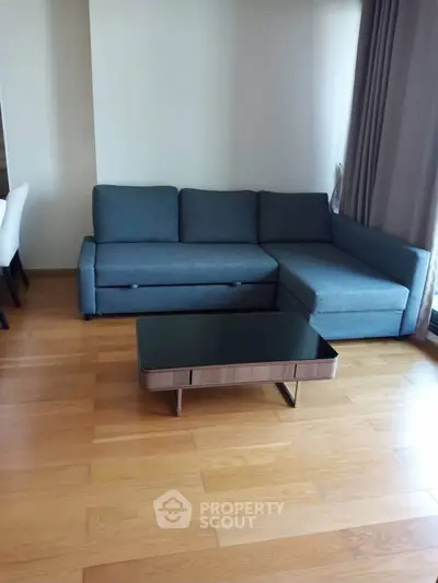 Modern living room with sleek gray sofa and stylish coffee table on polished wooden floor.