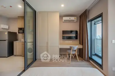 Modern studio apartment with open layout, featuring a compact kitchen and balcony access.