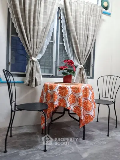 Cozy small dining area with vibrant orange tablecloth and elegant metal chairs