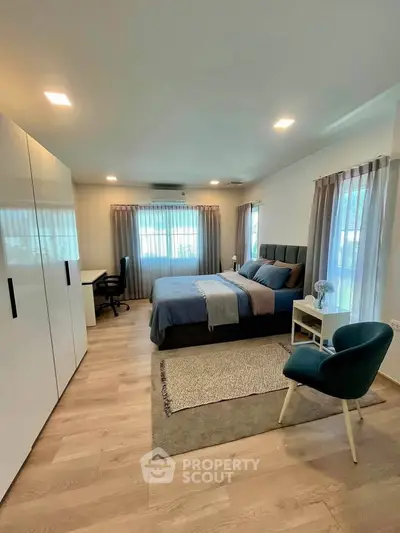 Spacious modern bedroom with stylish decor and ample natural light, featuring a cozy bed and elegant furnishings.