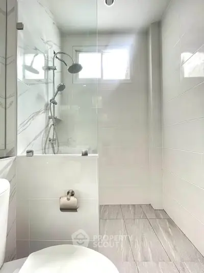 Modern bathroom with sleek white tiles and glass shower enclosure