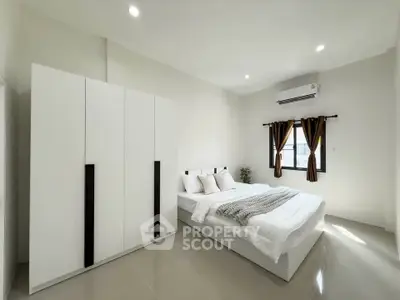 Spacious modern bedroom with sleek white furniture and natural light