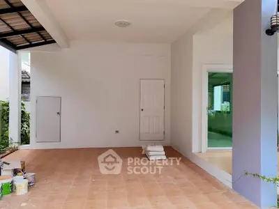 Spacious covered patio area with tiled flooring and white walls, perfect for outdoor relaxation.