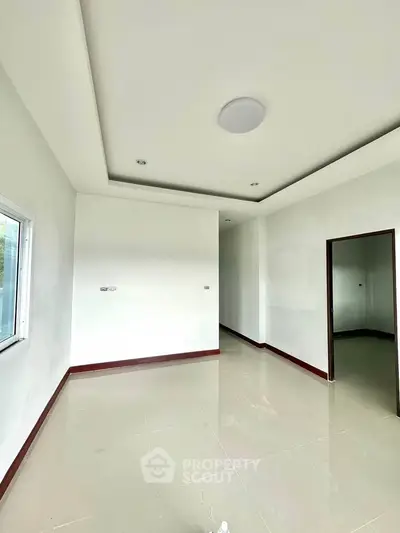 Spacious unfurnished room with modern ceiling design and large window, perfect for customization.