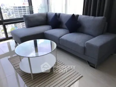 Modern living room with stylish gray sofa and glass coffee table in high-rise apartment.
