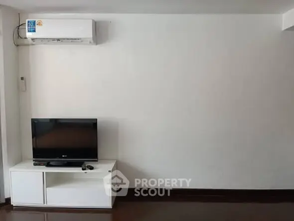 Minimalist living room with TV and air conditioner, perfect for cozy relaxation.