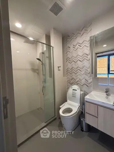Modern bathroom with glass shower and stylish vanity in contemporary apartment.