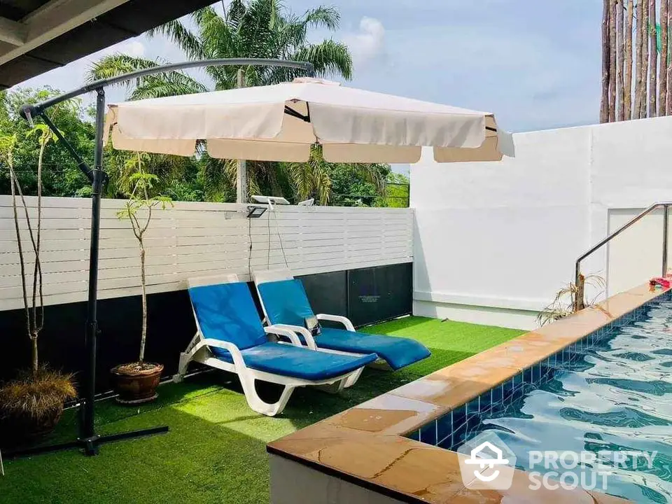 Luxurious private pool with sun loungers and lush greenery in a serene backyard setting.