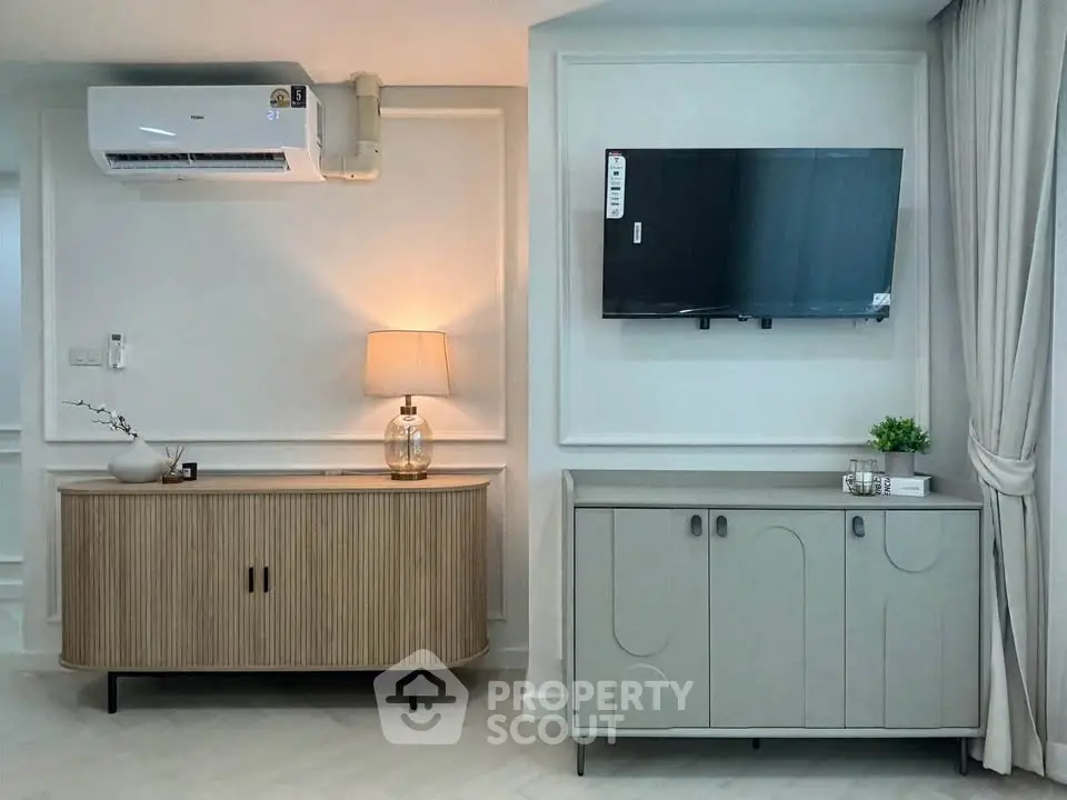 Modern living room with stylish furniture and wall-mounted TV, featuring elegant lighting and air conditioning.