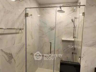 Modern bathroom with glass shower enclosure and marble tiles