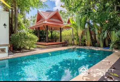 Tropical oasis with a sparkling pool and traditional pavilion, surrounded by lush greenery for ultimate relaxation.