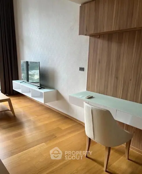 Modern living room with wooden flooring, wall-mounted TV, and sleek furniture design.