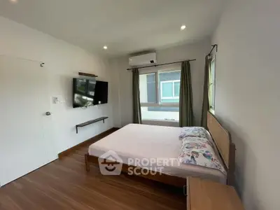 Modern bedroom with wooden flooring, wall-mounted TV, and large window for natural light.