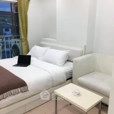 Cozy bedroom with modern decor and balcony view, featuring a laptop on the bed.