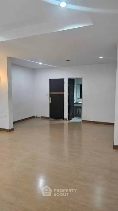 Spacious empty living room with wooden flooring and modern lighting, ideal for customization.