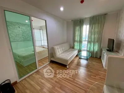 Modern living room with wooden flooring and glass sliding doors to bedroom