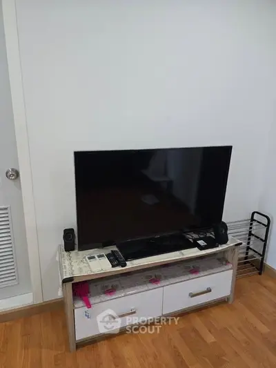 Modern living room with sleek TV setup and wooden flooring, perfect for cozy entertainment.