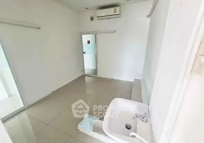 Minimalist bathroom with white tiles and modern fixtures, featuring a sleek sink and glass shower door.