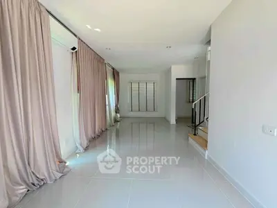 Spacious and bright living room with elegant curtains and tiled flooring.
