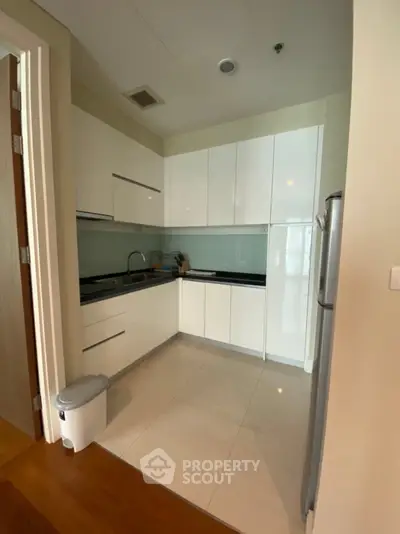 Modern kitchen with sleek white cabinets and stainless steel appliances in a cozy apartment.