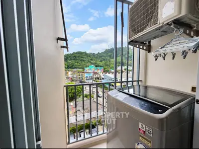 Charming balcony with scenic view and modern washing machine in urban apartment.
