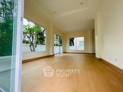 Spacious empty room with large windows and wooden flooring, ideal for customization.