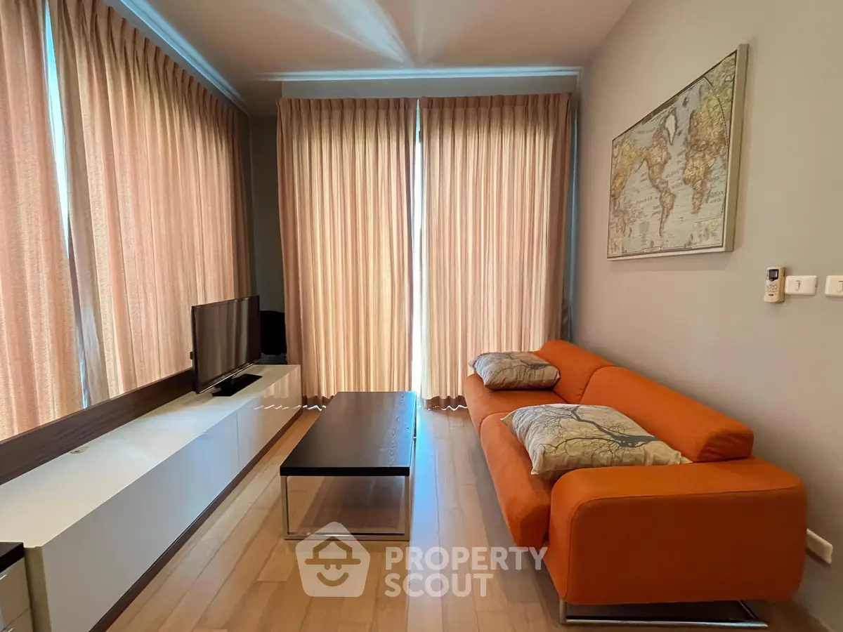 Modern living room with orange sofa, wall map, and natural light from large windows.