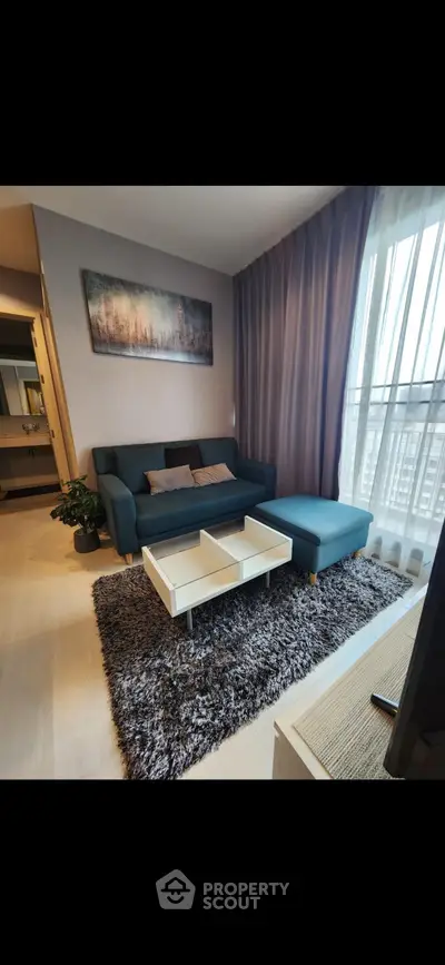 Modern living room with stylish sofa, cozy rug, and large window for natural light.