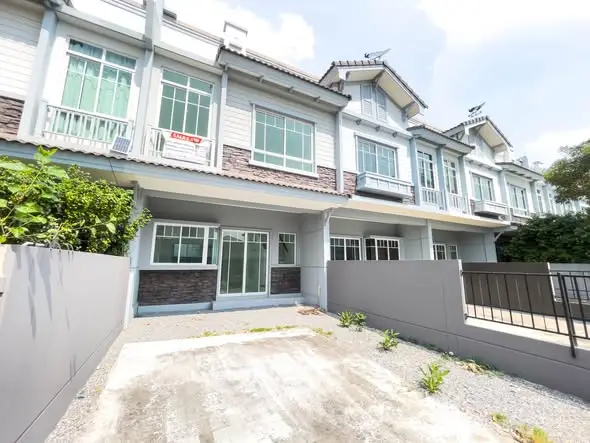 Charming townhouse exterior with modern design and spacious driveway in a serene neighborhood.