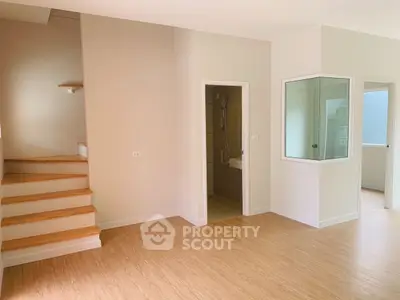Spacious modern interior with wooden flooring and staircase, ideal for customization.