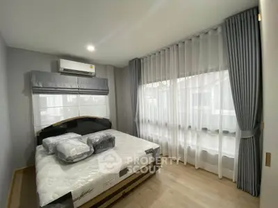 Modern bedroom with large windows and stylish curtains, featuring a comfortable bed and air conditioning.