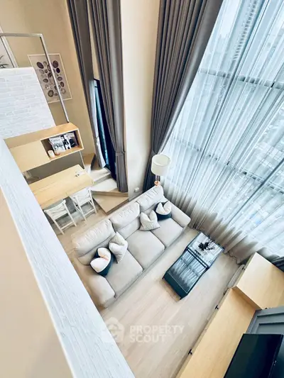 Luxurious high-ceiling living room with floor-to-ceiling windows and modern decor.