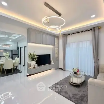 Luxurious modern living room with elegant lighting and open layout to dining area.