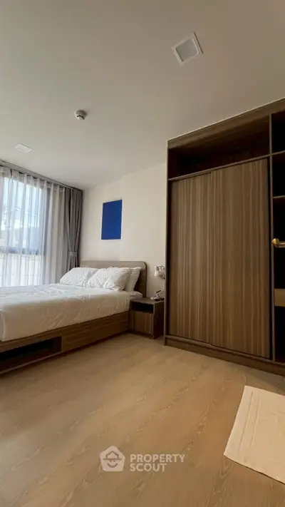 Modern bedroom with wooden flooring, large wardrobe, and natural light from window.