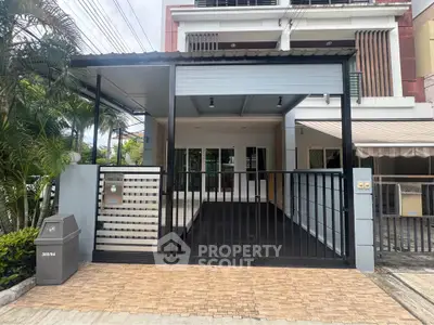 Modern townhouse exterior with gated driveway and lush greenery