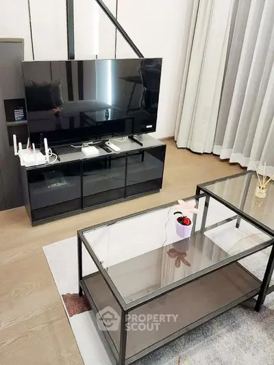 Modern living room with sleek TV stand and glass coffee table, perfect for contemporary urban living.