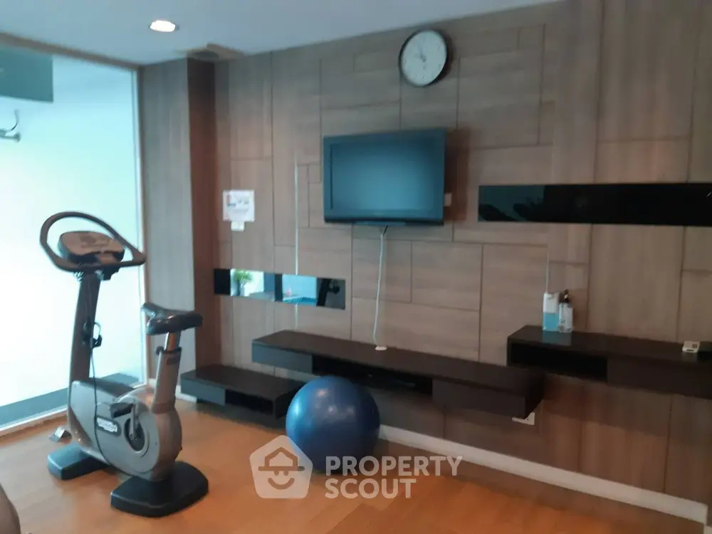 Modern gym with exercise bike and wall-mounted TV in luxury apartment building